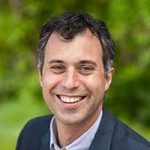 Male doctor with brown hair smiling in head shot