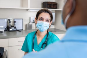 Masked Nurse Speaks to Patient