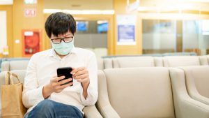 Male patient using smartphone in a clinic waiting room