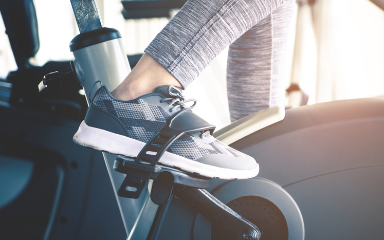 Woman feet is cycling on fitness exercising bike machine