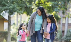 Hispanic mother taking her two girls to school