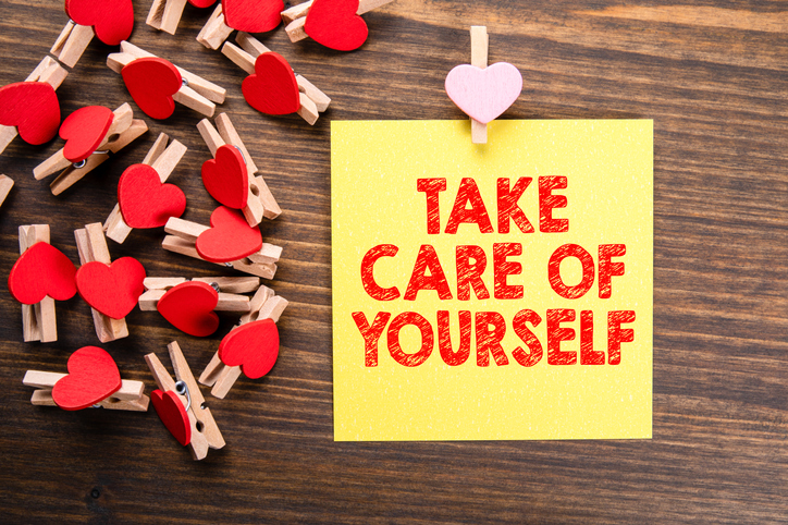 Take Care Of Yourself Written on a yellow sticky note with red hearts