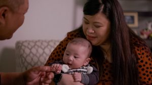 Asian couple sit on couch while doting on their baby boy