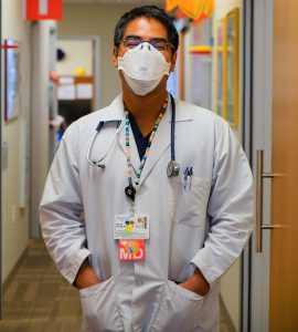 Dr. Brian Prystwosky stands in his office hallway in his white doctor's coat