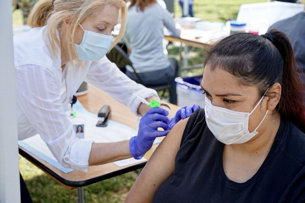 Latina woman gets vaccinated at a vaccine pop up by Sutter Health and Raizes Collective