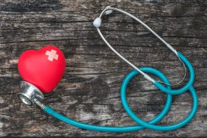 Concept with red heart love with cross bandage and medical doctor physician's stethoscope