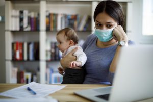 Worried mother with face protective mask working from home