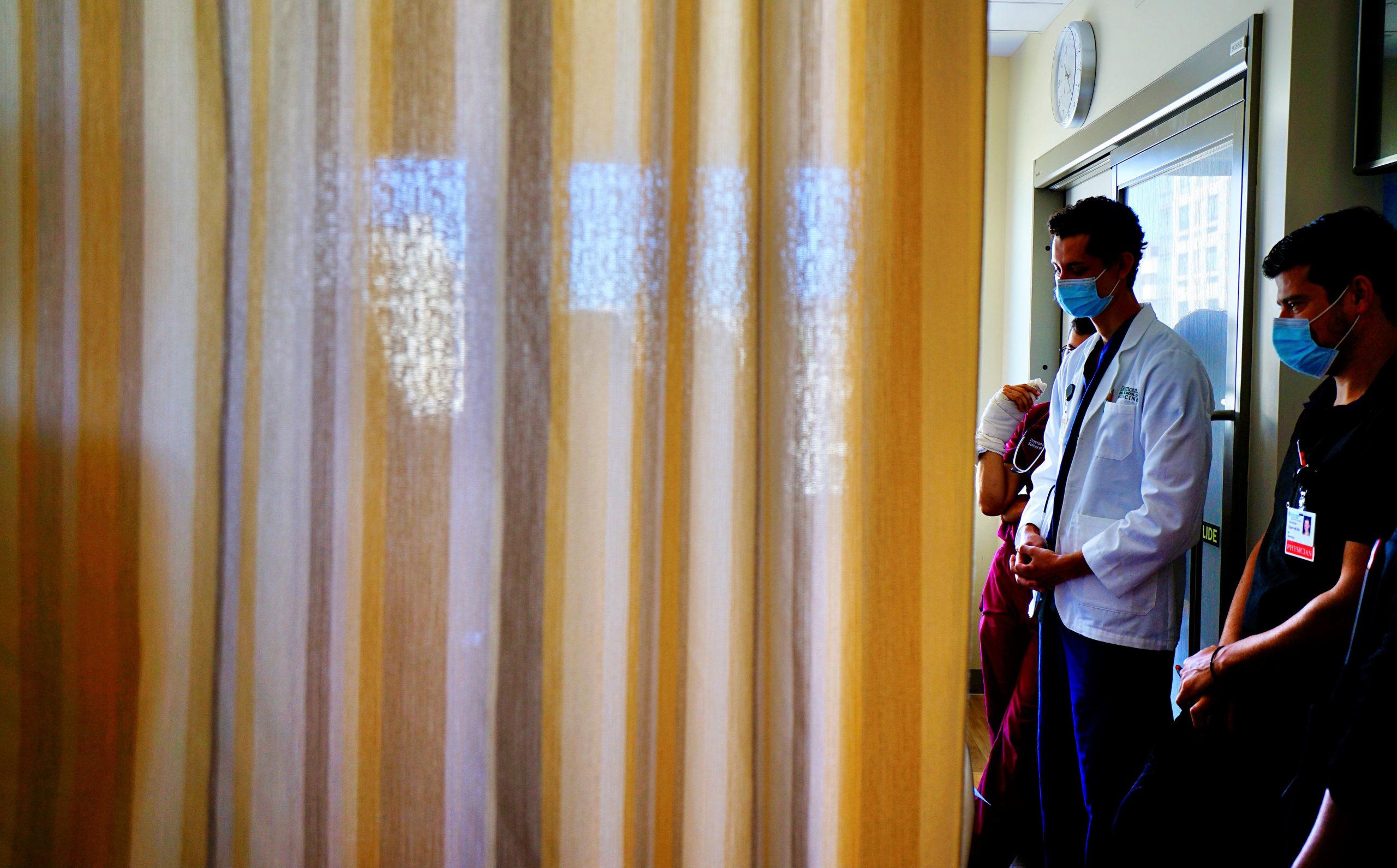 Residents greet a patient behind their bed curtain