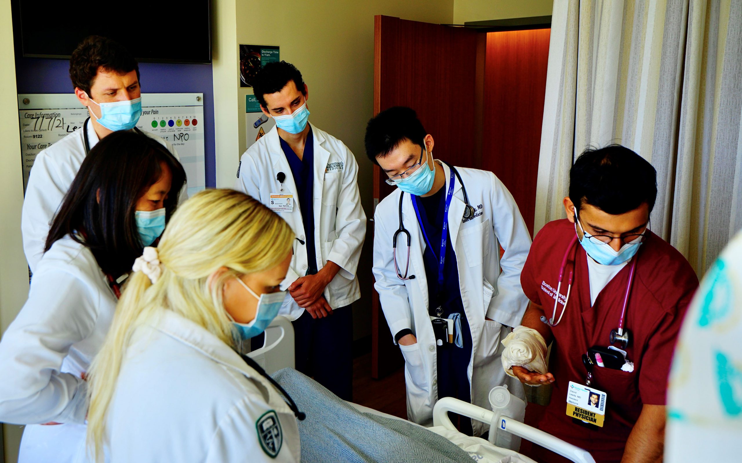 Residents gather at the patient's bedside to discuss care and treatment plans for the day