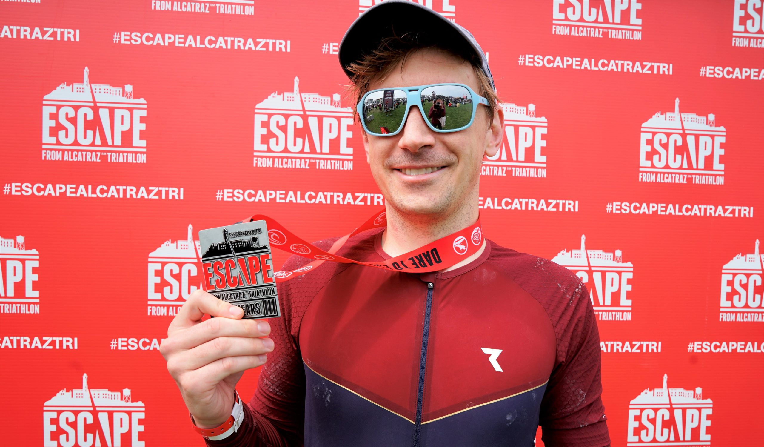 Scott Grubb proudly holds his Escape from Alcatraz Triathlon medal in the finishers circle
