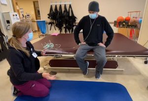 Physical therapist directs patient on exercises inside rehab gym