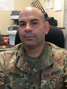 Bald, Caucasian man in Army fatigues sitting at desk
