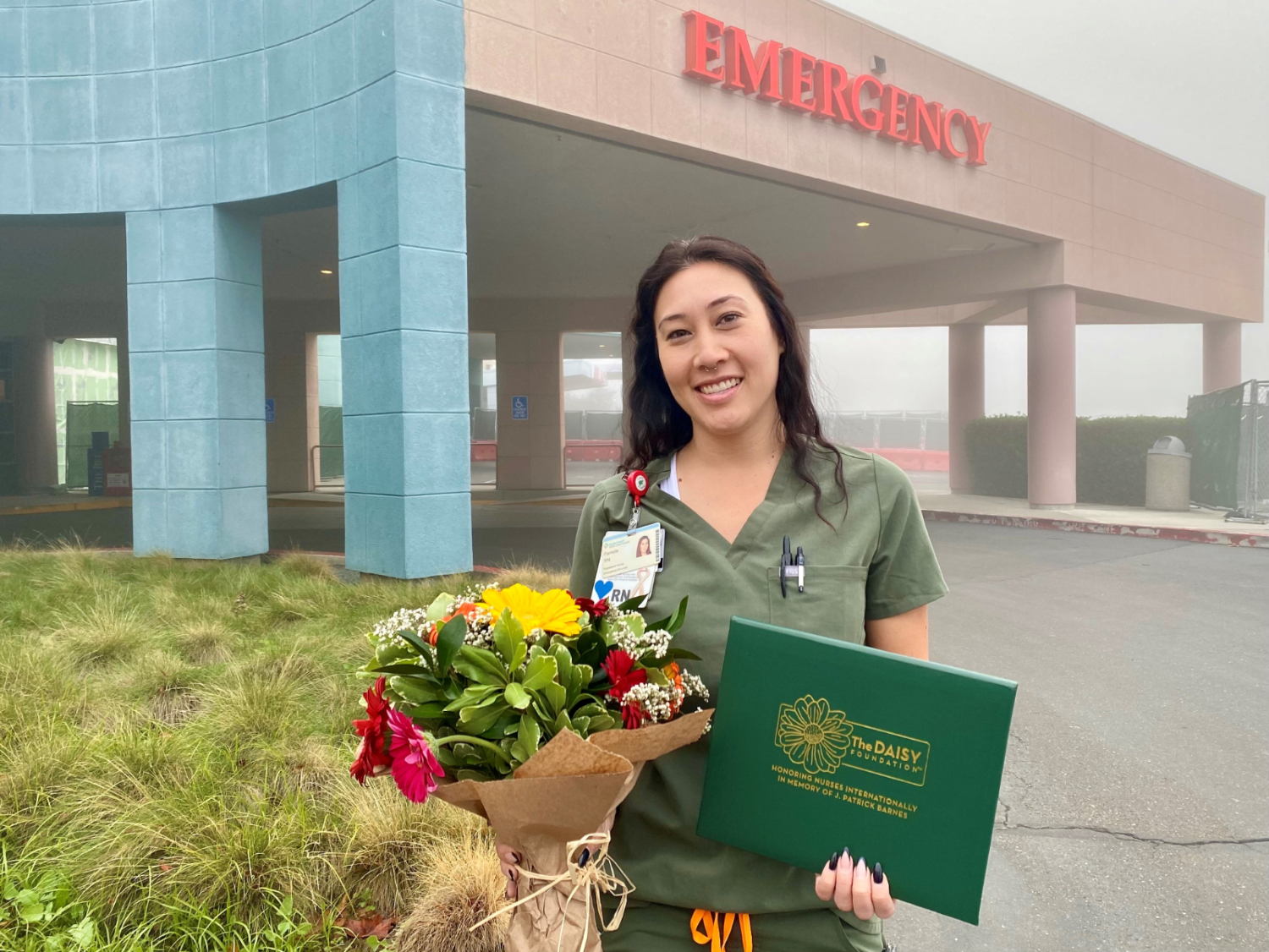 Sutter Davis Hospital emergency department nurse Pam Blankenship poses with flowers and her DAISY Award outside the hospital.
