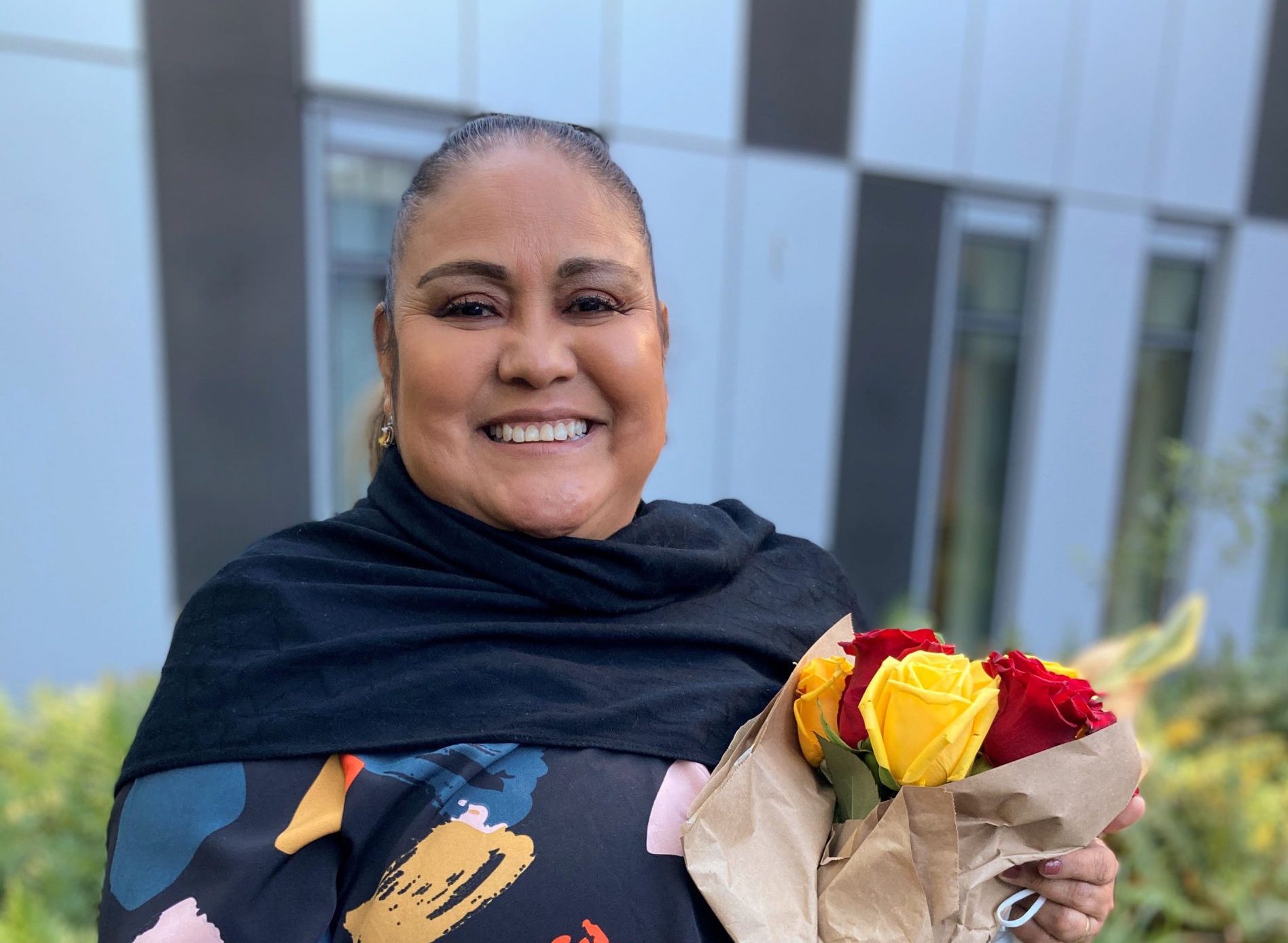 Hilda Martinez stands with roses at her send-off event for the Rose Parade