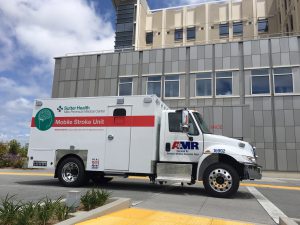 An ambulance, designated as a Mobile Stroke Unit because of its specialized equipment and medications, is parked in front of a hospital.