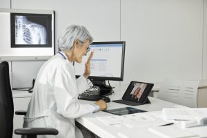 Doctor waving at a patient who is on an iPad