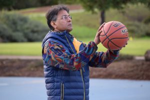 Older man in a vest prepares to shoot a basketball. 
