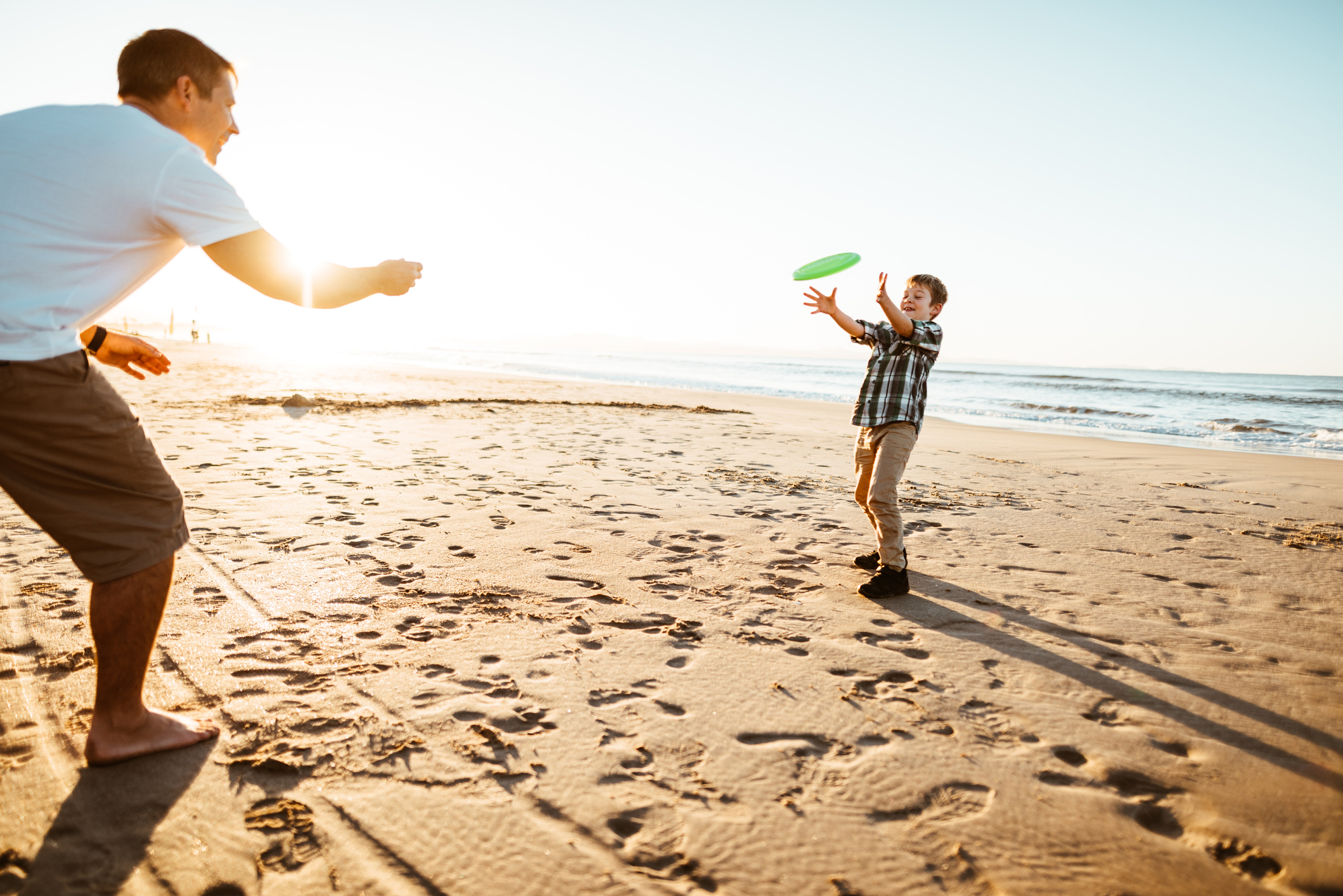 father and son playing fresbee at the beach - stock photo