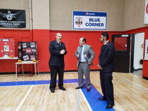 Three men in a gymnasium standing and talking