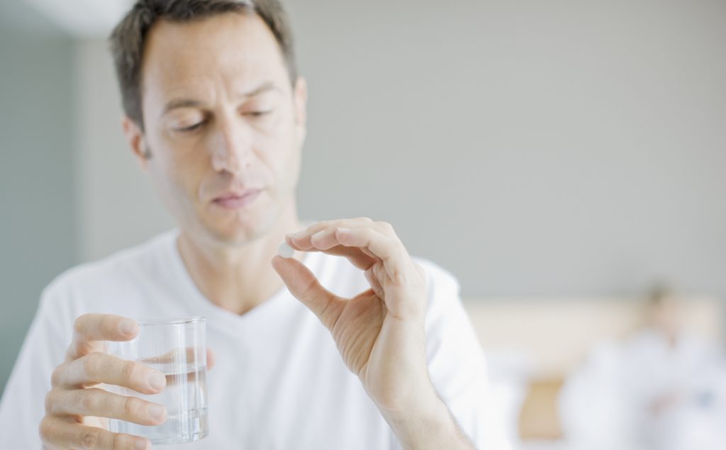 Man holding aspirin and glass of water.
