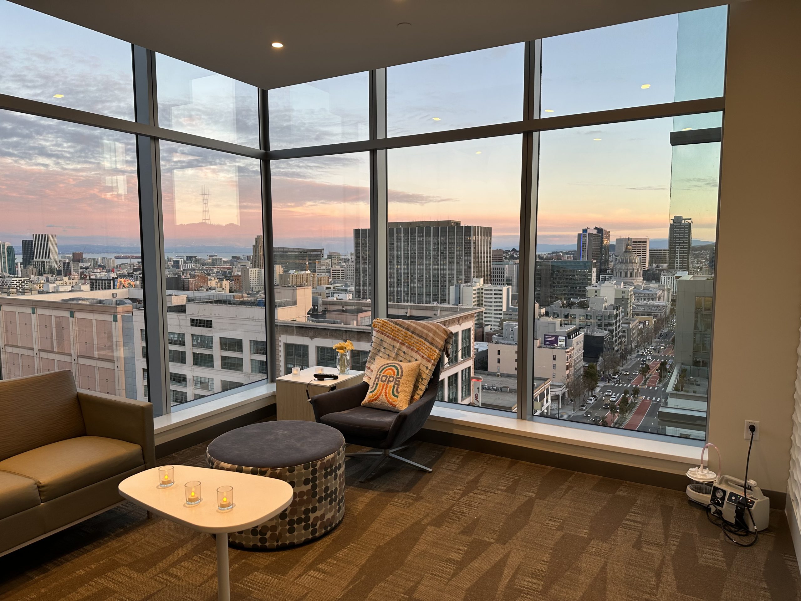 A hospital patient and family lounge with floor to ceiling windows and city views of downtown San Francisco.