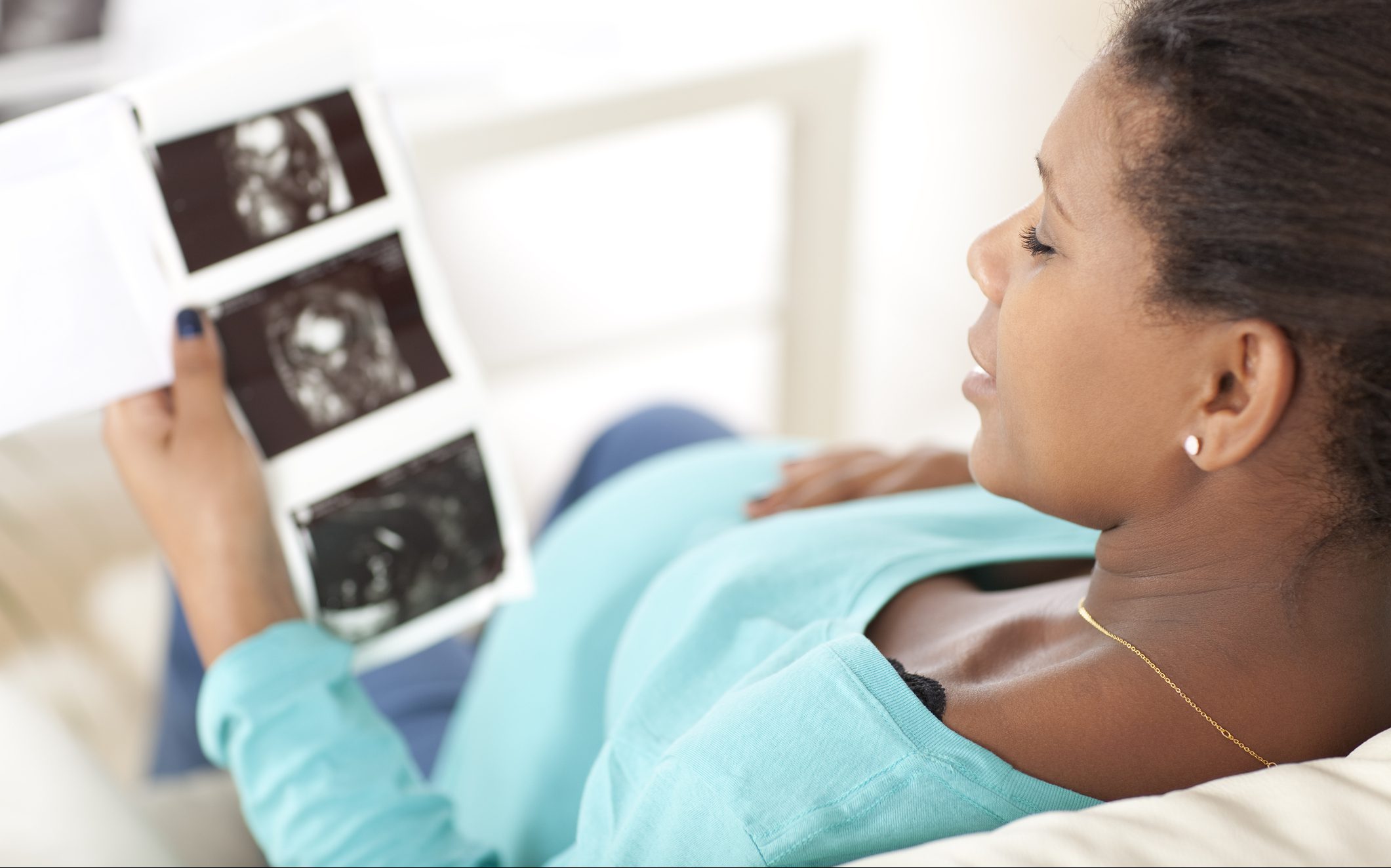 Black pregnant woman holding images of fetus