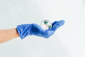 A hand in a medical glove holds a glass globe