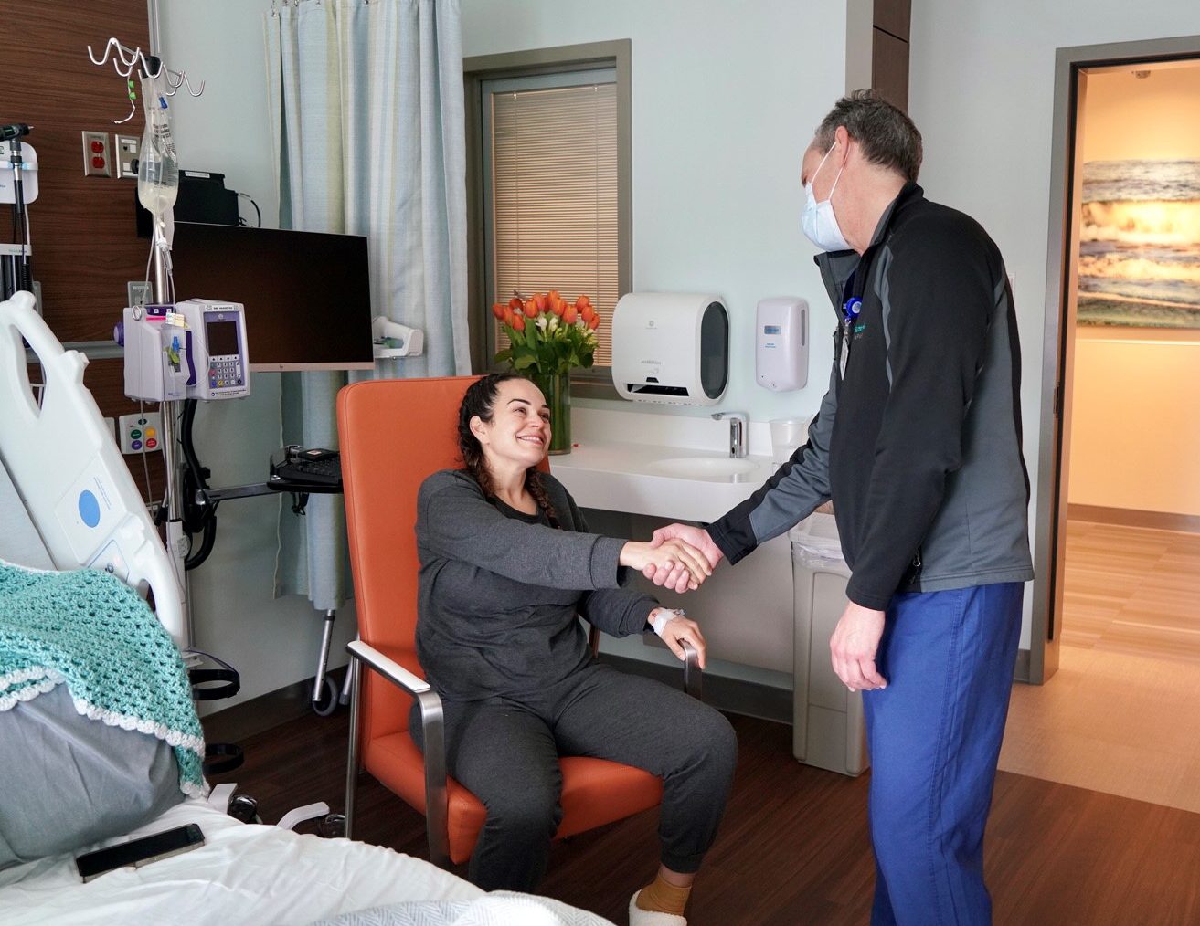 Danielle Rojas sits in her patient room recovering from donating her kidney and her doctor shakes her hand in a show of appreciation.