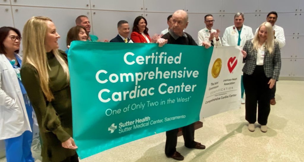 Heart team members unfurl banner with patient Mick Doughty