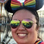 Asian woman wearing multicolored reflecting sunglasses and Minnie Mouse ears with a rainbow bow