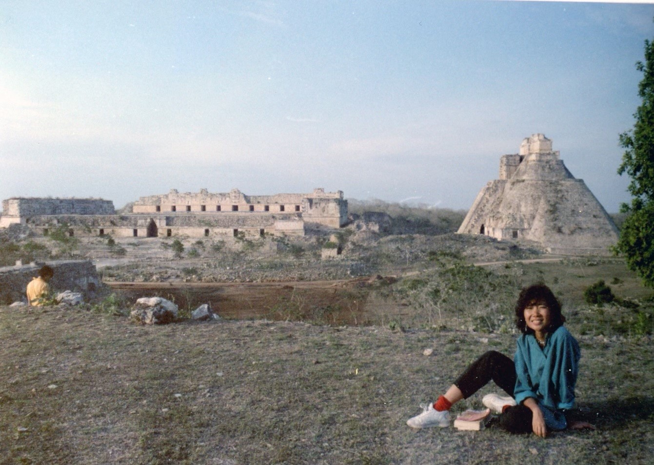 A picture of a young Asian woman in the foreground with ancient ruins in the background. 