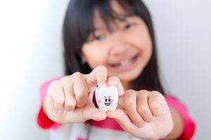 Asian girl holding a tooth toy with a smiling face
