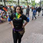 Dark-haired woman with black T-shirt, rainbow scarf and hip belt