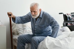 Older Caucasian man in pajamas gets out of bed