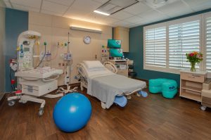 Hospital labor and delivery room with bed, bassinet, traditional medical equipment and other laboring support tools