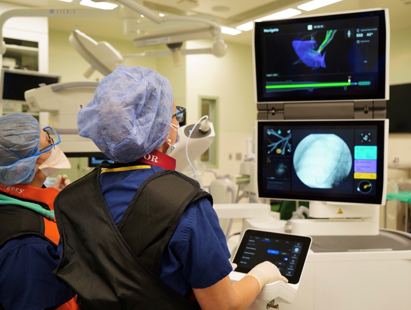 A doctor and nurse in surgery operating a sophisticated piece of technology that allows the surgical team to see inside a patient's lungs.