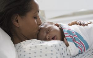 Close up of young latin woman kissing her new born at hospital bed