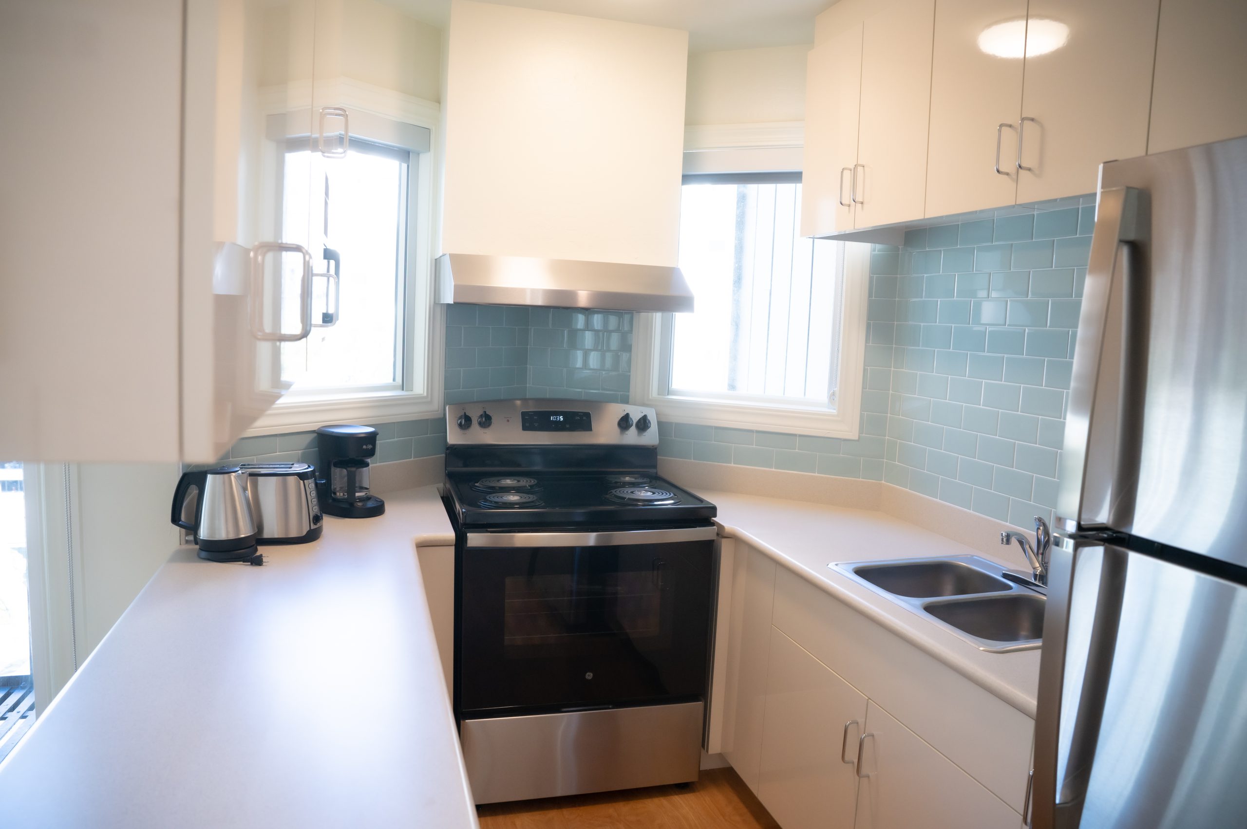 A brightly colored kitchen with blue tiles, lots of countertop space and a stovetop