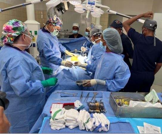 A group of doctors and nurses perform a liver procedure on a patient in an operating room