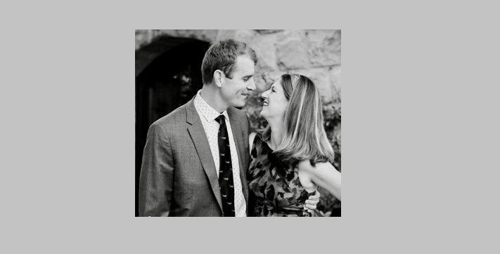 Black and white candid of man and woman happily gazing and smiling at each other with gray border surrounding the photo