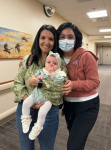 A mom and her baby pose with the nurse who saved the baby's life