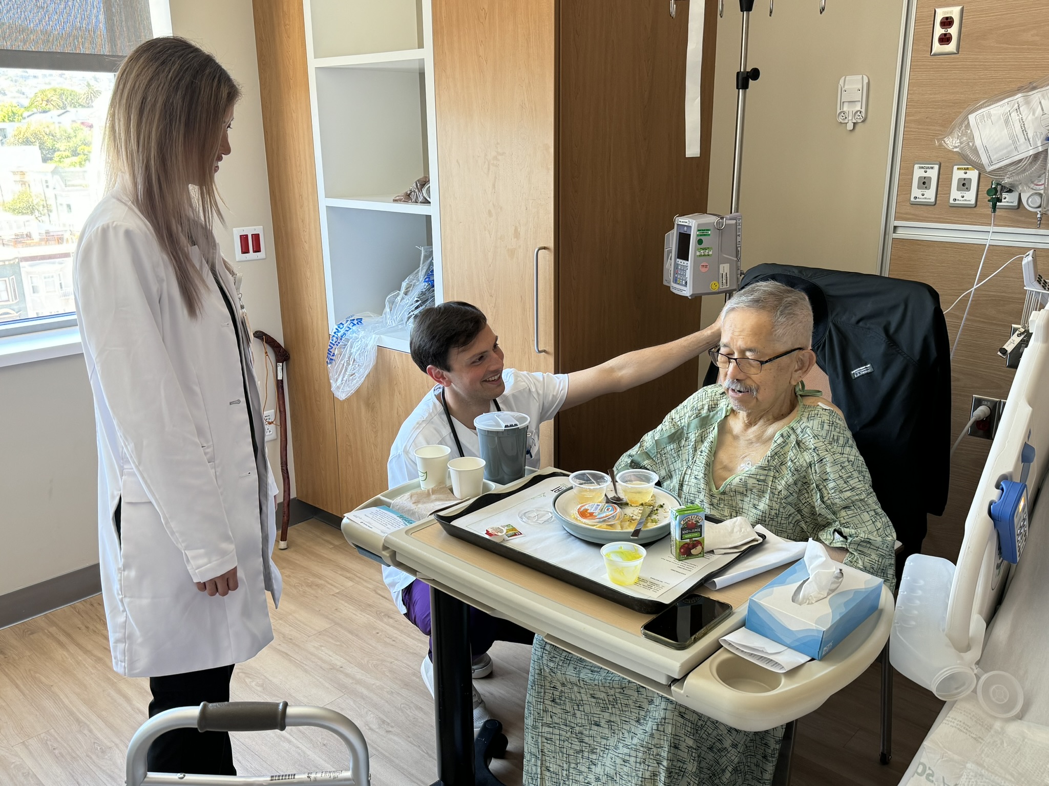 A nurse and nursing student in conversation with a patient