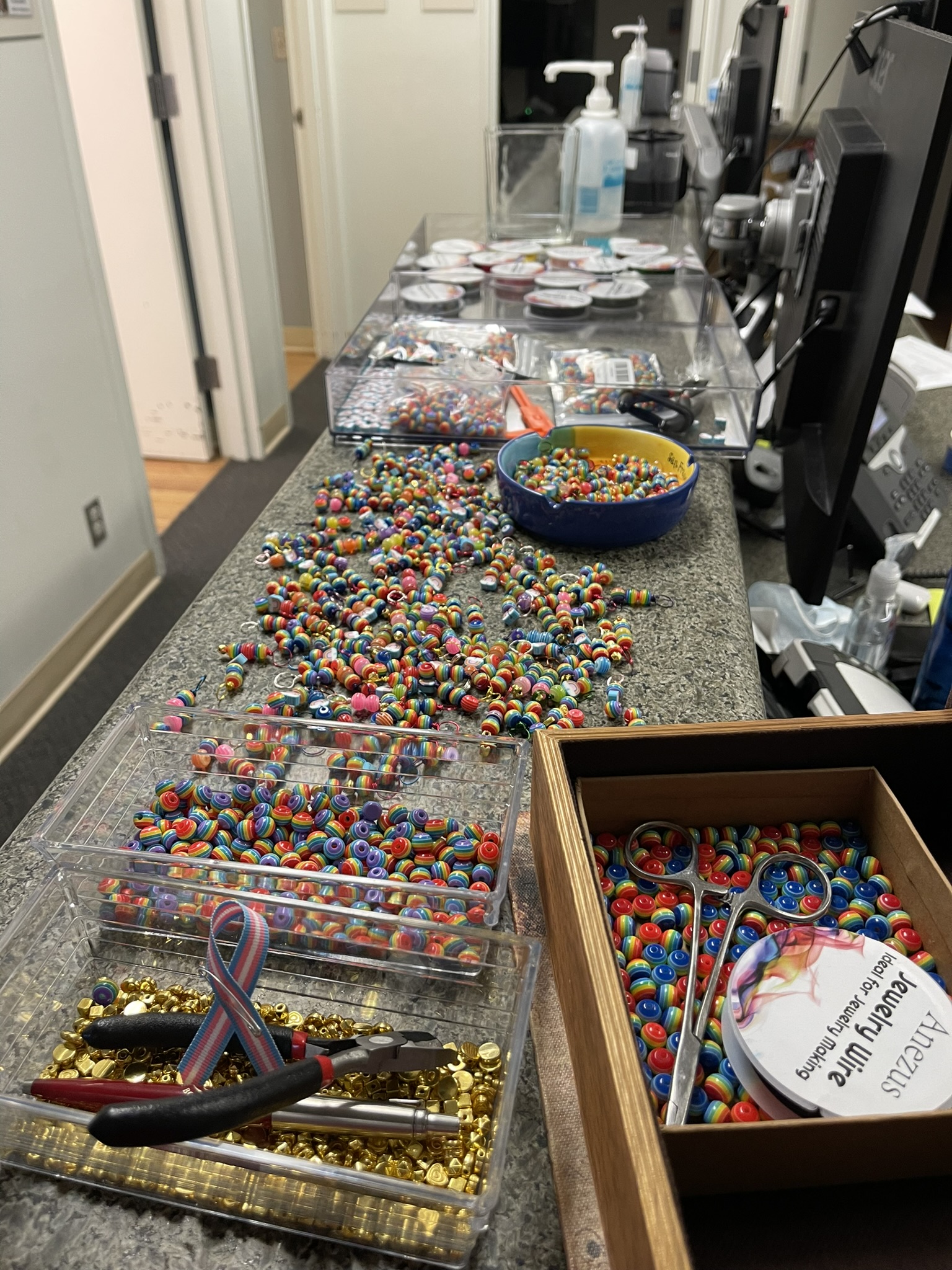 Colorful rainbow beads, jewelry wire and craft containers fill an office workspace