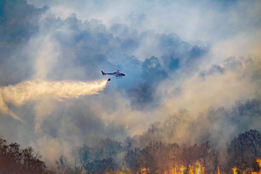 Helicopter drops water on wildfire.