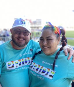 Kat and Wes posing together in Pride shirts at a Bay FC Pride night.