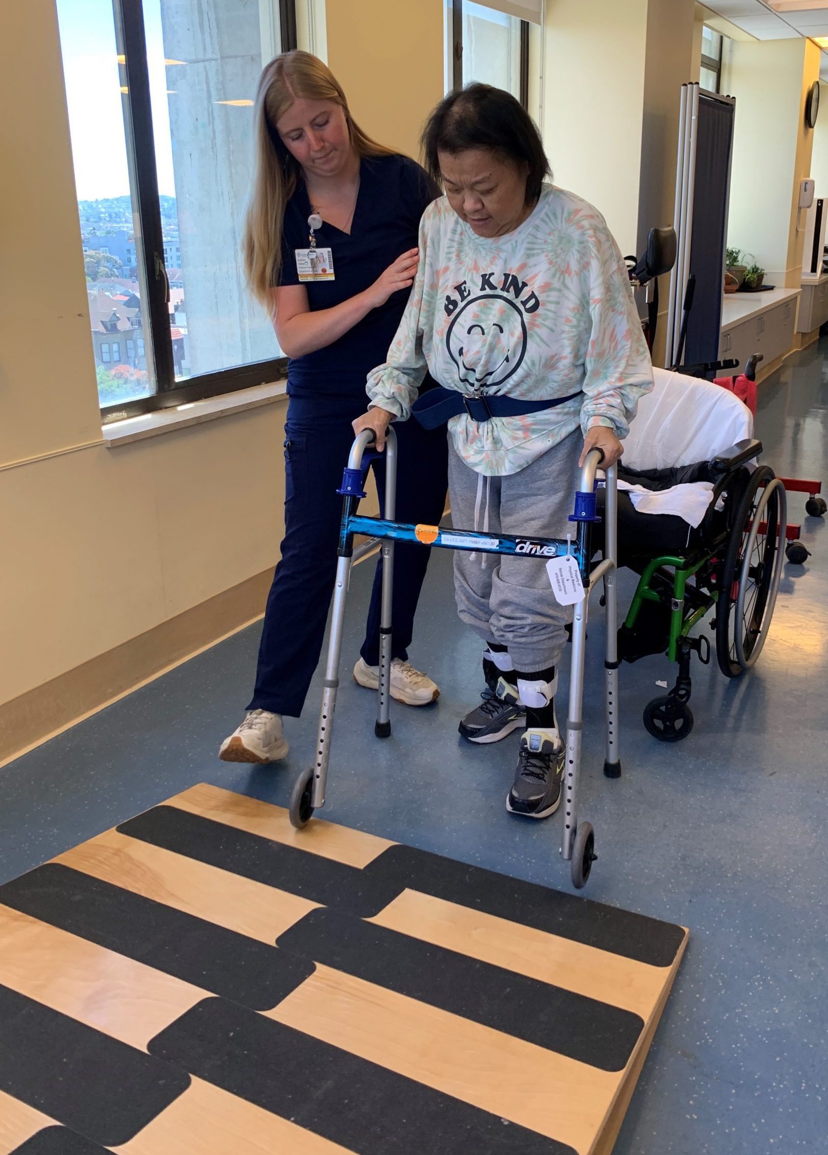 Woman receives help walking from a healthcare worker in a hospital rehabilitation center