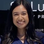 Smiling Latina woman with long dark hair and navy blue scrubs