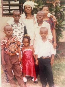 Black family pose for a photo alongside house