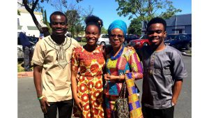 Black family with two sons, daughter and mother pose for a photo during a sunny day in a parking lot