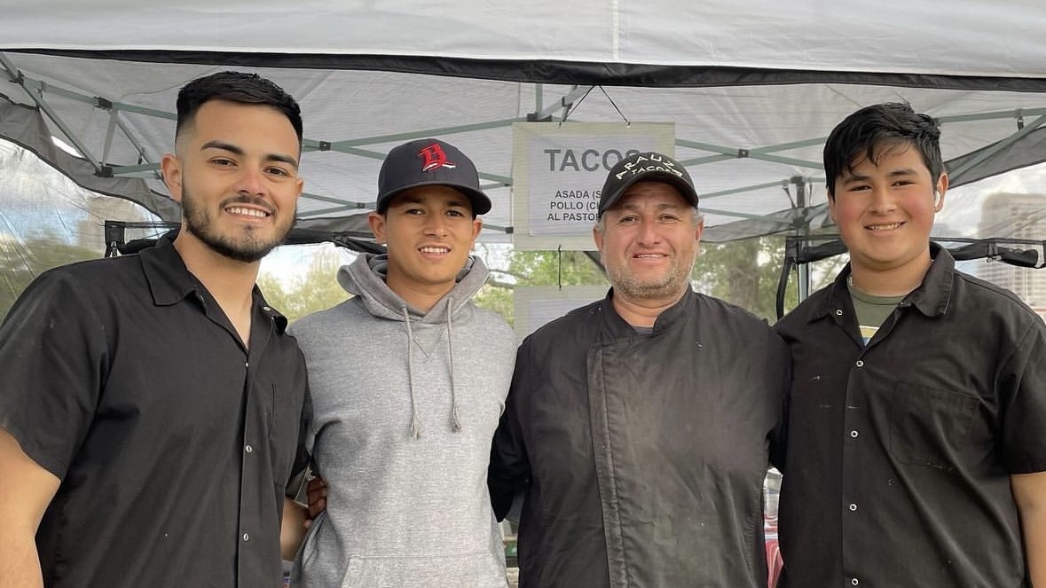 Four Latino men pose for picture underneath a tent